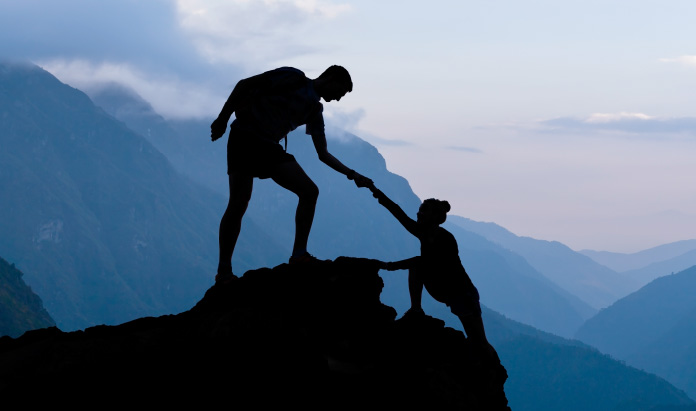 Man helping woman up a mounta